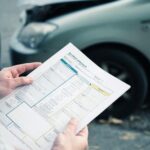 Current image: Close-up of hands signing a car insurance settlement agreement in Philadelphia.