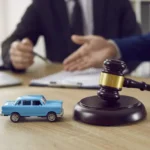 Current image: Judge’s gavel and car keys on a legal desk symbolizing an insurance dispute.